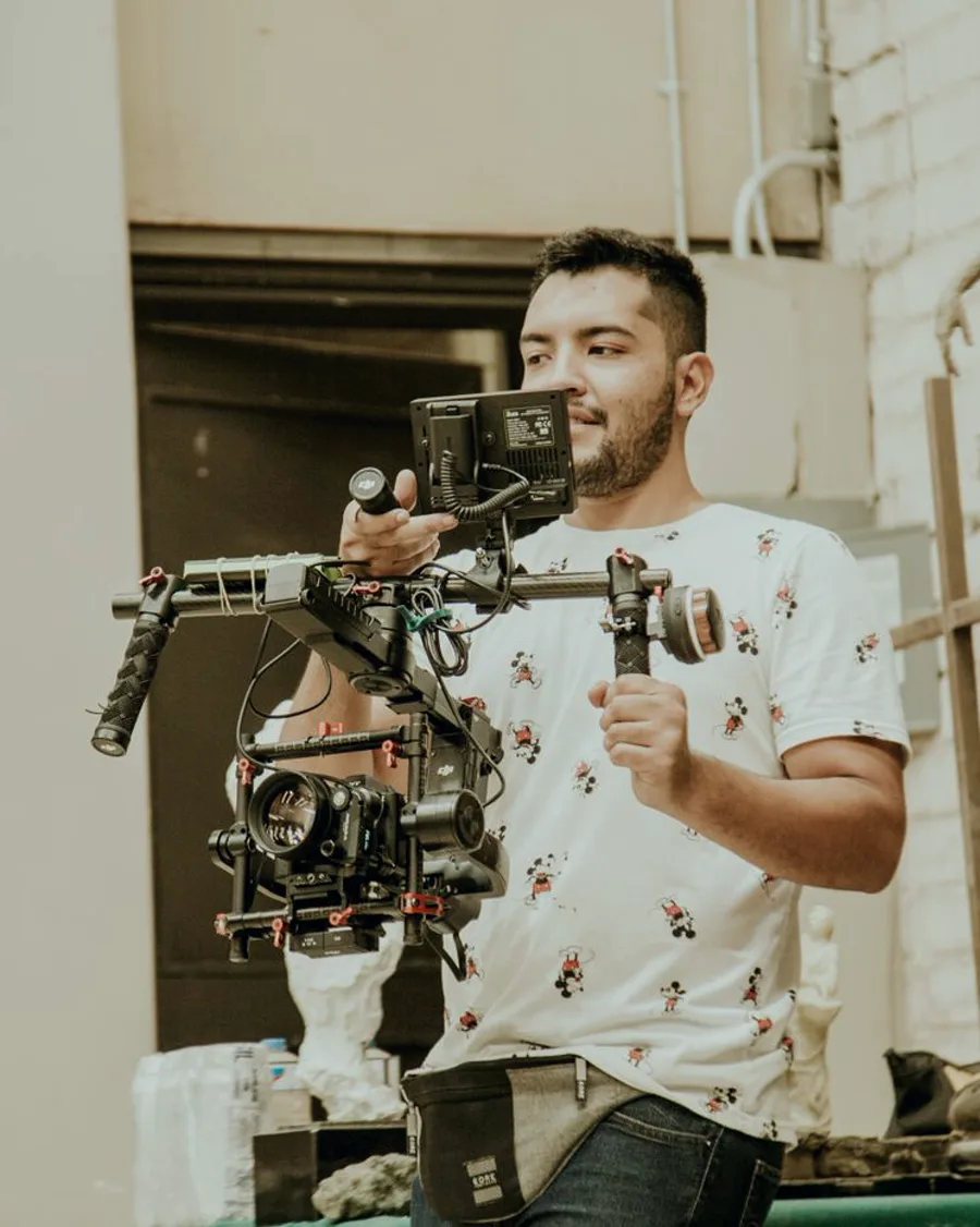 A videographer filming with a handheld gimbal rig